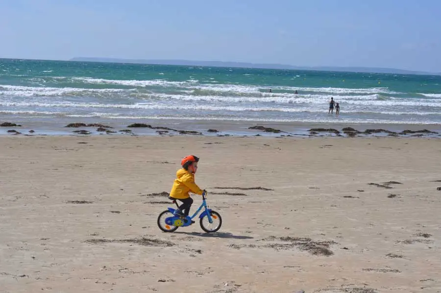 How to Teach Bike - child riding a bike on the wet sand of the beach